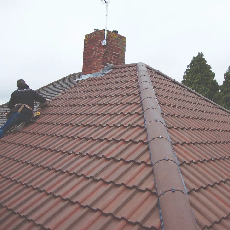 Roofer working along the ridge of a tiled roof